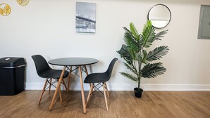 A room with a round table and four chairs, a potted plant, a cityscape painting, and a round mirror on the wall. - 1Bed/1Bath_KingBed Central+W/D+WIFi (Philadelphia)