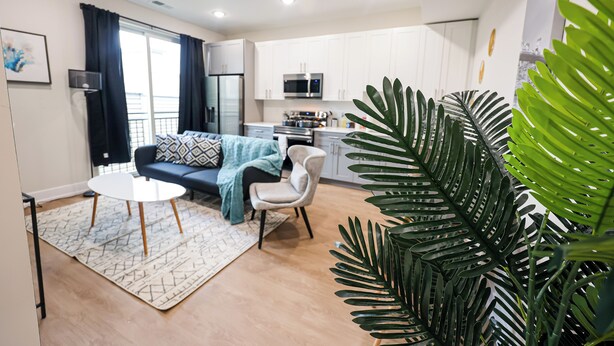 A modern living room with a sofa, coffee table, and a large plant. - 1Bed/1Bath_KingBed Central+W/D+WIFi (Philadelphia)