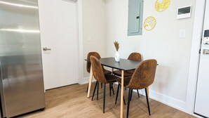 Una cucina moderna con frigorifero in acciaio inossidabile, un tavolo da pranzo in legno con quattro sedie e un vaso con piante essiccate a parete.