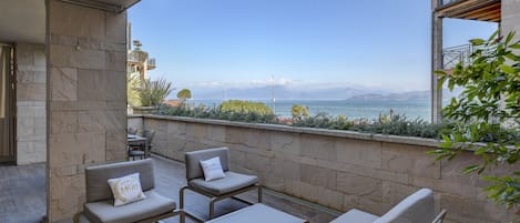 Ein Balkon mit Blick auf das Meer, Steinmauern und Gartenmöbeln.
