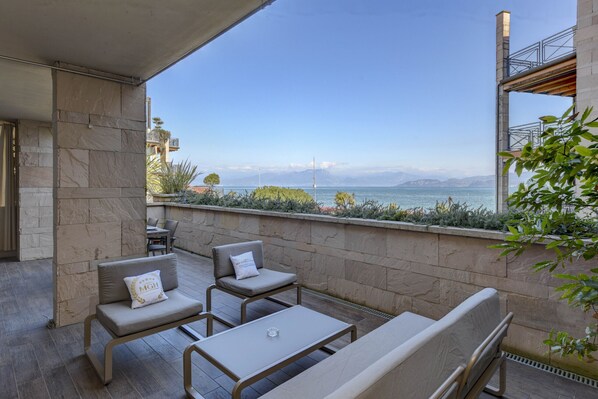 A balcony with a view of the sea, stone walls, and outdoor furniture.