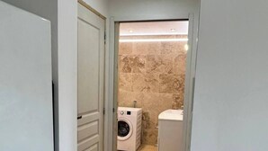 A narrow hallway leading to a bathroom with a washing machine and a toilet. - LA MAISON DU SOLEIL MAGNIFICENT NEW EQUIPPED T3 IN PORTICCIO (Grosseto-Prugna)