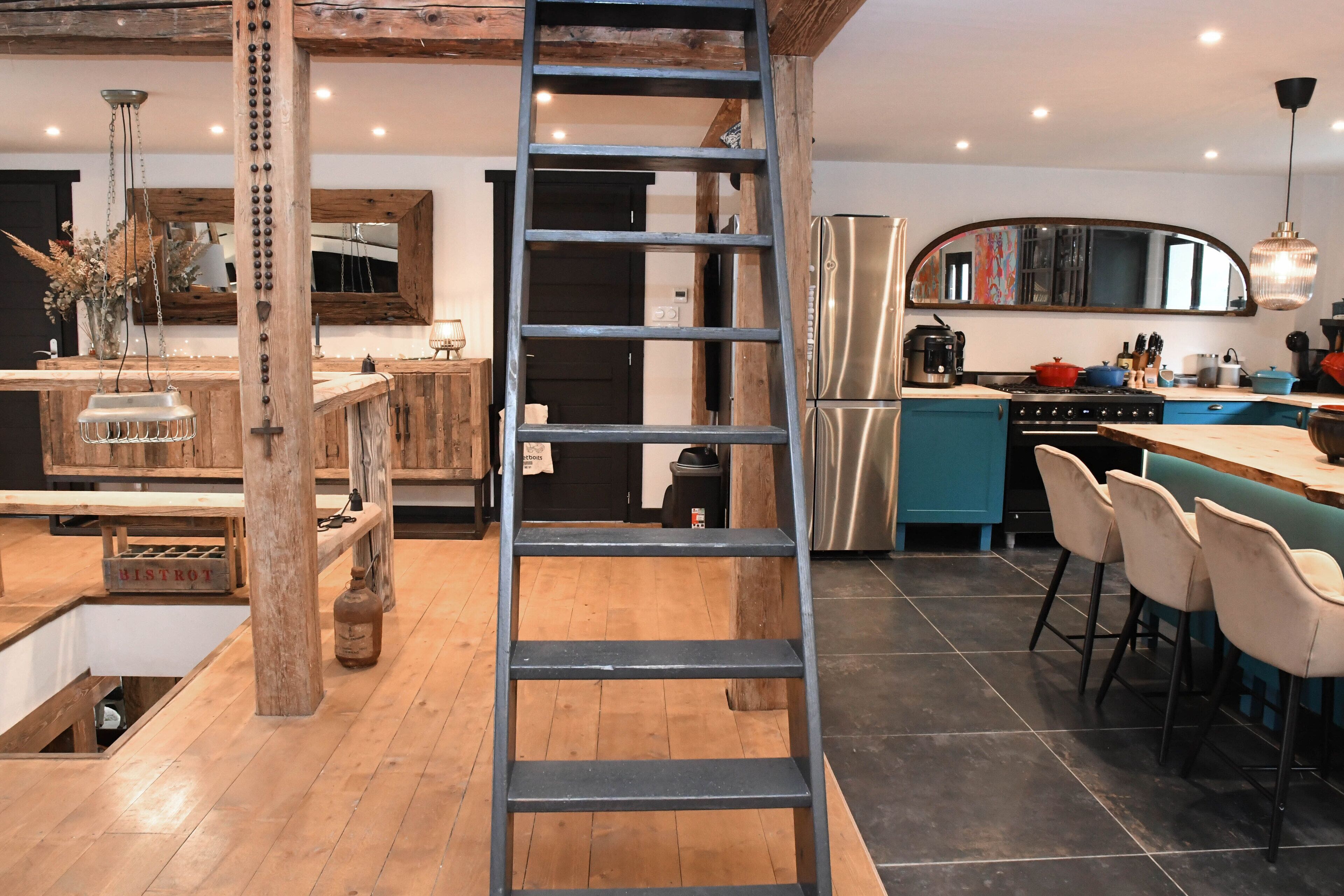 Una cocina con una escalera de madera, un refrigerador de acero inoxidable y una encimera azul.