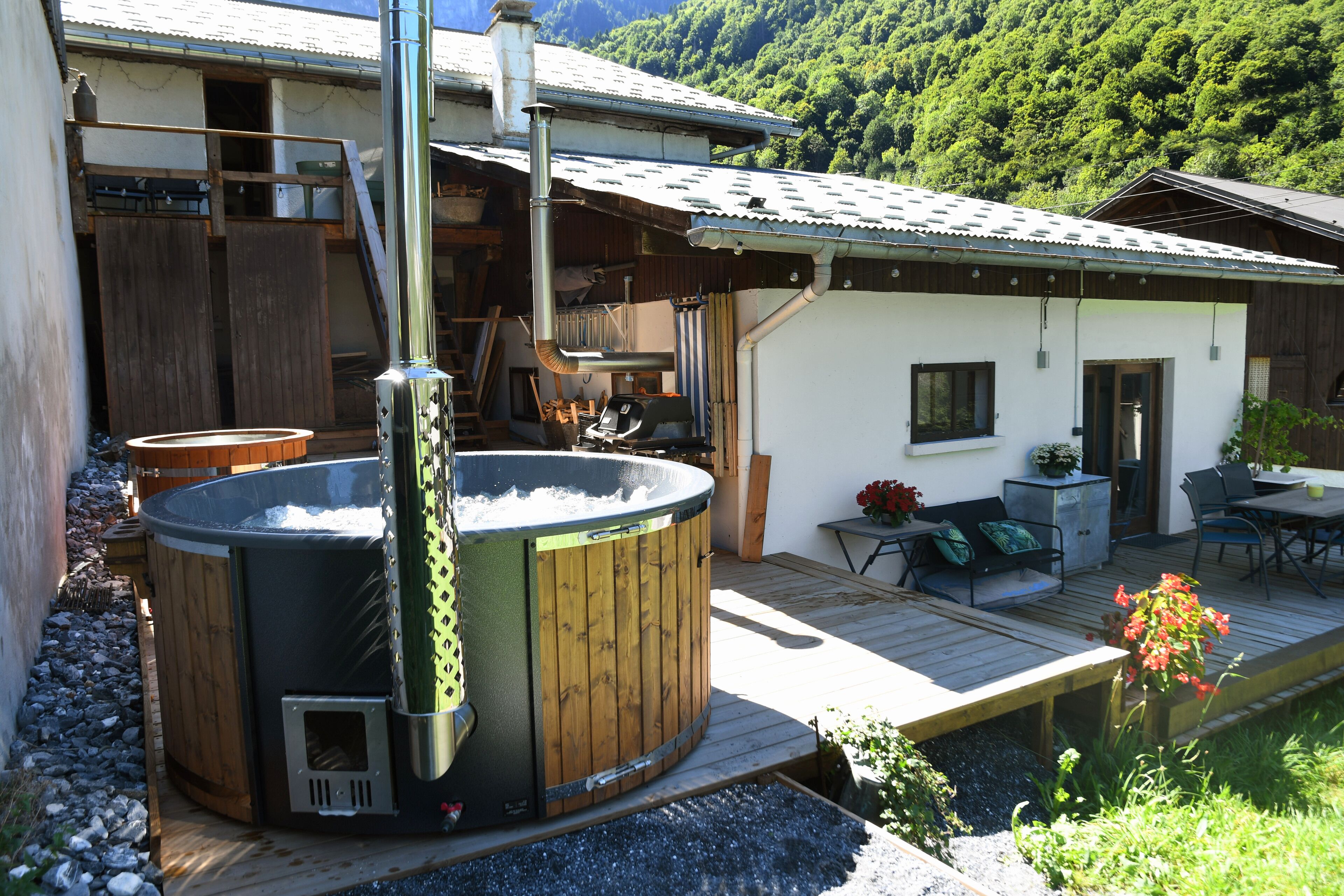A hot tub on a wooden deck with a wooden house in the background.