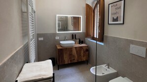 Een moderne badkamer met een houten wastafelmeubel, een grote spiegel, een wastafel en een toilet.