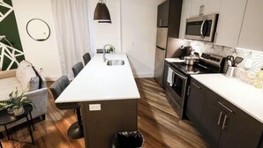 Una cocina moderna con una isla central, armarios oscuros y un microondas sobre la encimera.