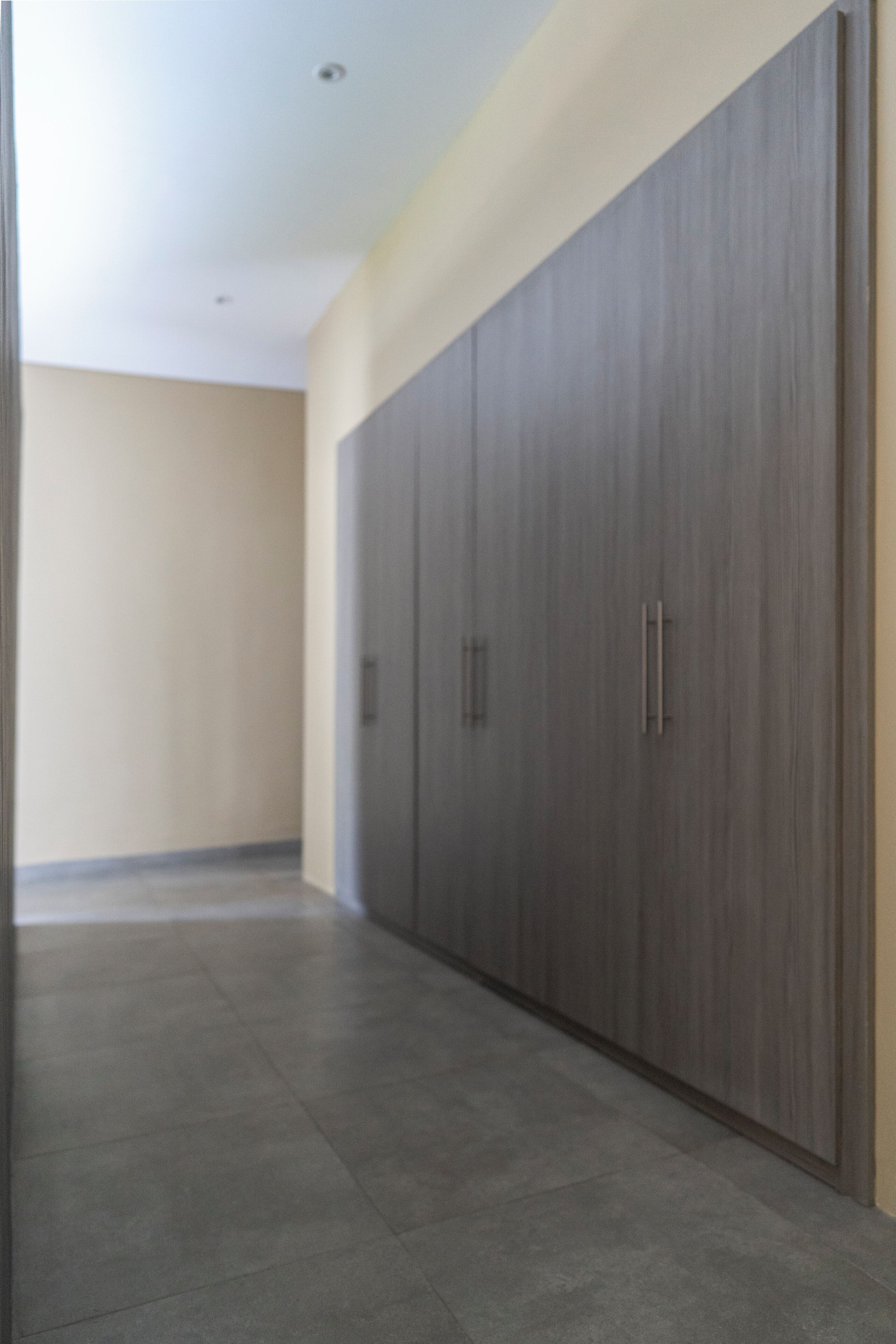 A hallway with a large wardrobe, a tiled floor, and a plain wall.