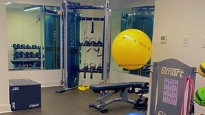 Un gimnasio con equipo de ejercicio, un espejo grande y un letrero de Smart Fitness.