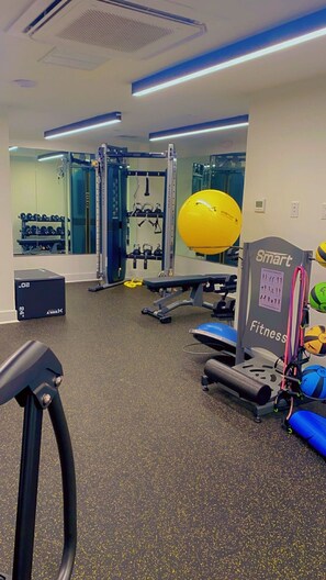 Una palestra con attrezzature per esercizi, uno specchio a parete e il cartello Smart Fitness.