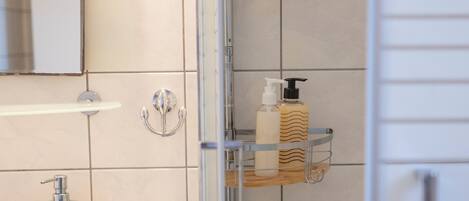 A bathroom with a white sink, a mirror, and two chrome shelves holding toiletries.
