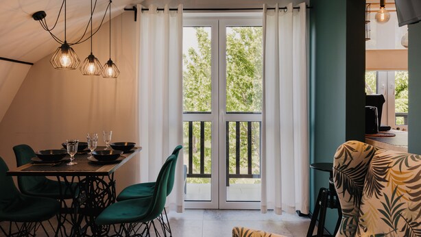 A dining area with a table set for four, chairs, and hanging pendant lights. - Apartamenty Sun & Snow Nadmorska (Rowy)