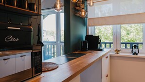 A modern kitchen with a built-in stove, coffee maker, and a view of the outdoors. - Apartamenty Sun & Snow Nadmorska (Rowy)