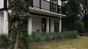 A modern two-story house with a balcony, surrounded by a well-maintained garden and tall grasses. - Apartamenty Sun & Snow Nadmorska (Rowy)