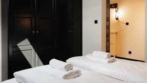 A hotel room with two beds, a wardrobe, and a wall-mounted light fixture. - Apartamenty Sun & Snow Nadmorska (Rowy)