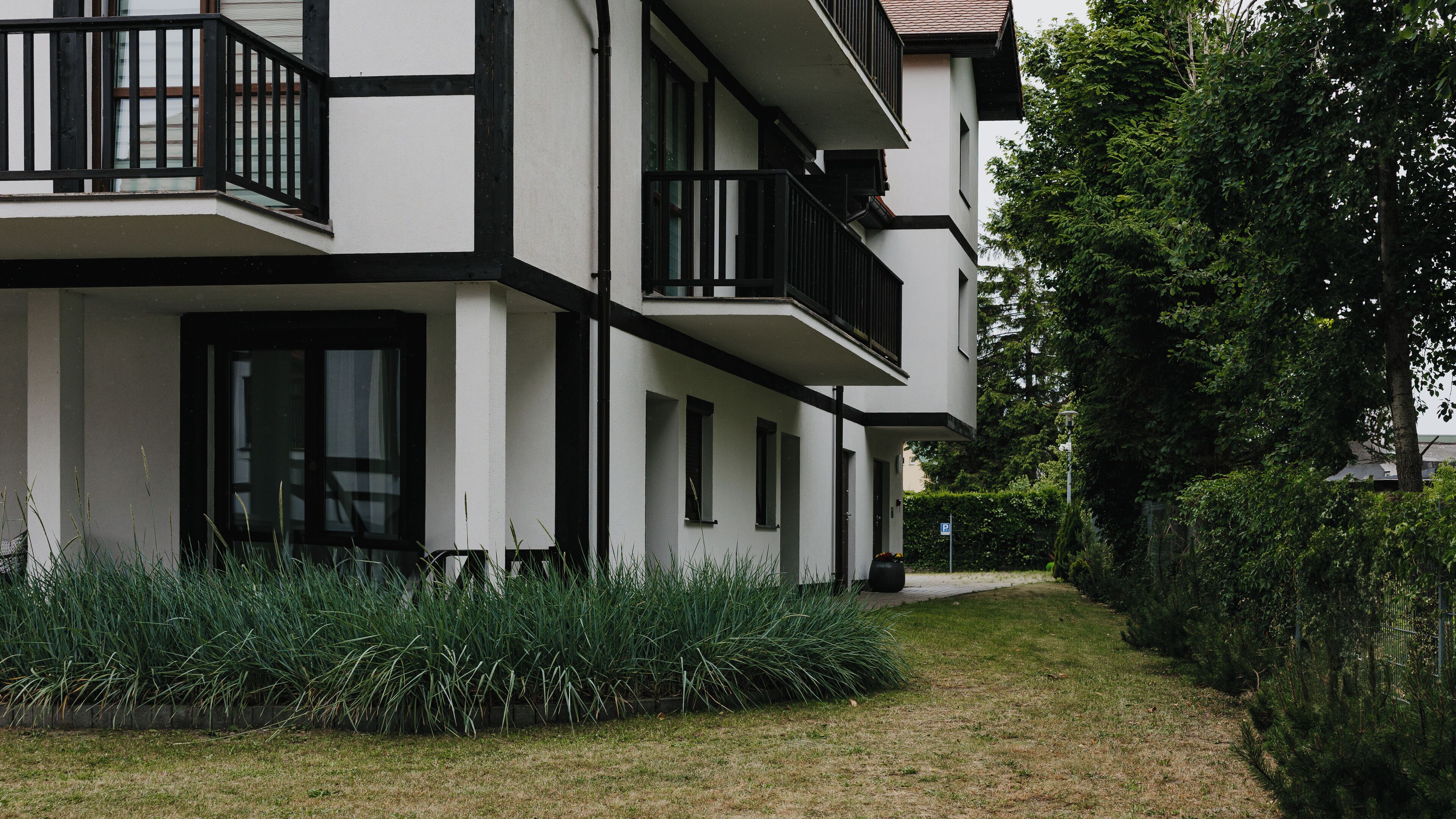 A modern two-story building with a white facade and black trim, featuring balconies and large windows.