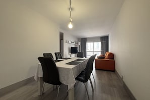 A modern dining area with a table, chairs, and a television.
