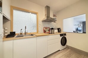 A compact kitchen with a sink, stove, and a washing machine.