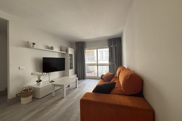 A modern living room with a flat-screen TV, a sofa, a coffee table, and a bench.