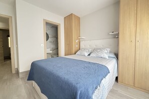 A bedroom with a bed, wooden wardrobe, and a door with a marble wall.