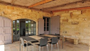A stone-walled outdoor dining area with a wooden ceiling, a table with chairs, and a bench. - Pool, relax, and Olives at Masseria Don Tommaso and its guesthouse (Specchia)