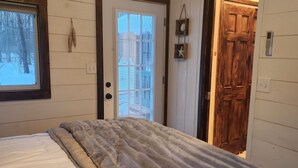 Un dormitorio con una cama, techo de madera, ventana y puerta.