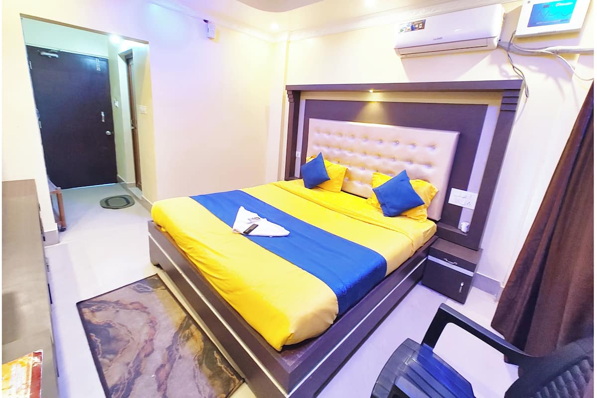 Una habitación de hotel con cama, mesita de noche y unidad de aire acondicionado.