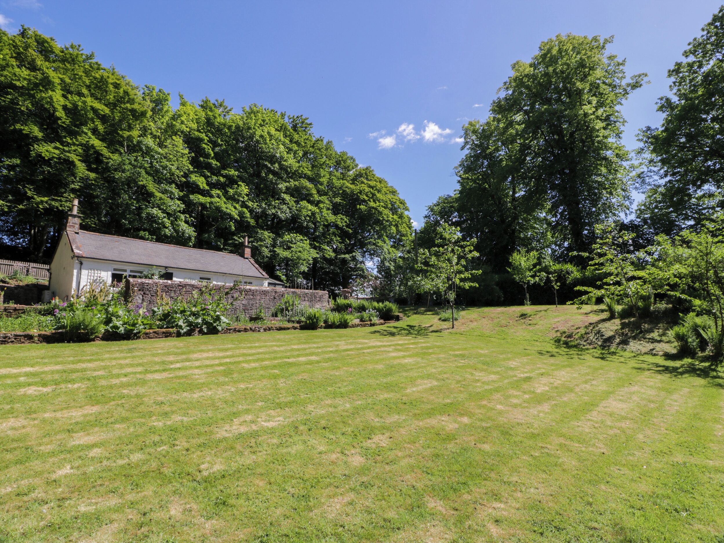 A house with a stone wall and a lawn in front.