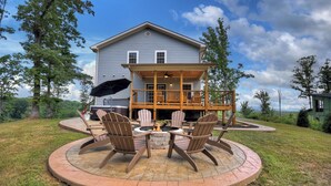 Une maison dotée d’une terrasse, d’un espace extérieur aménagé avec des chaises Adirondack et d’un foyer.