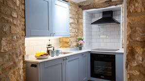 A kitchen with stone walls, a built-in oven, and a coffee maker on the counter. - Little Forge  - Romantic retreat in Bourton-on-the-Water (Bourton-on-the-Water)