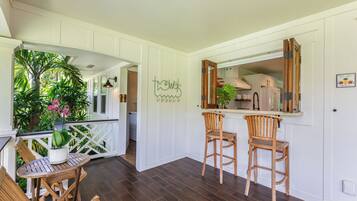 A kitchen with wooden chairs, a bar area, and a view of the outdoors.
