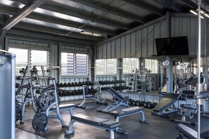 Un gimnasio con diverso equipo de ejercicio, incluyendo mancuernas, bancos y máquinas de pesas.