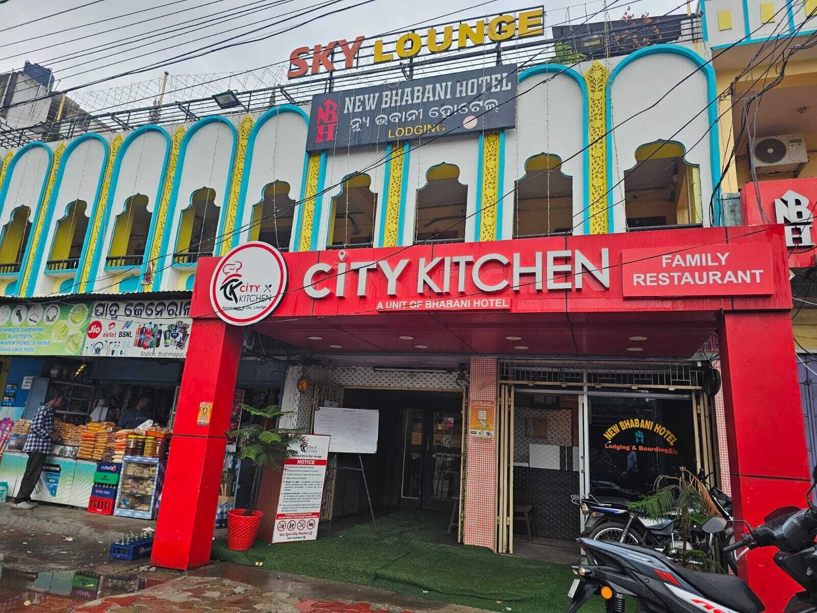 A hotel with a red and white facade, named 'City Kitchen', and a sign indicating it is a family restaurant.
