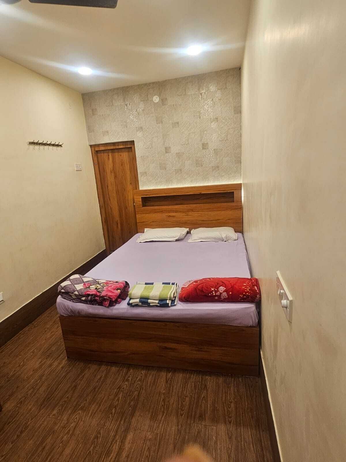 A bedroom with a wooden bed, a small wooden wardrobe, and a textured wall.