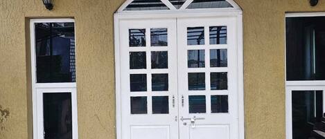 A building with a white door, two windows, and a wooden floor.