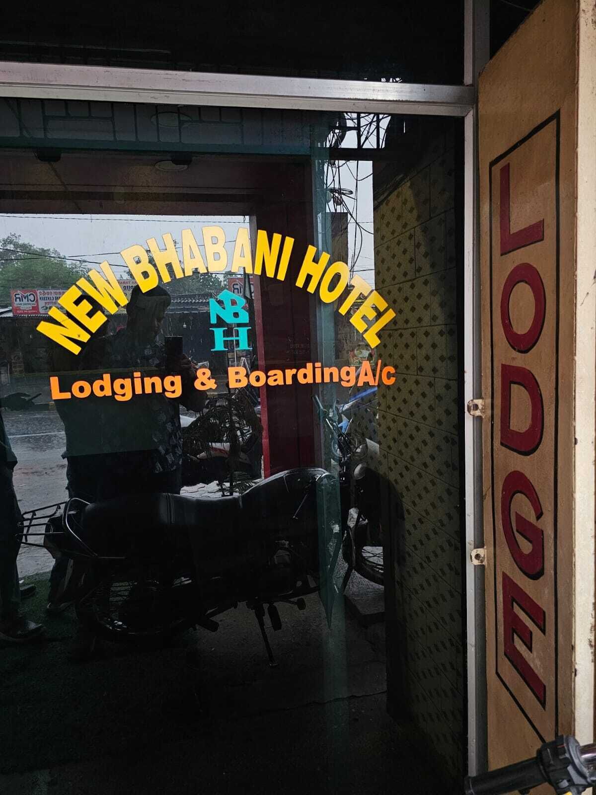 The entrance of New Bhabani Hotel with a sign indicating it offers lodging and boarding services.