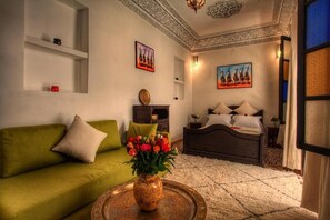 A room with a green sofa, a bed with white bedding, a vase with flowers, and a decorative ceiling. - Calla Lilly, Riad 111 and Spa (Marrakech)