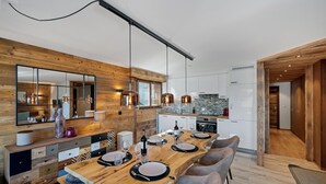 A modern kitchen with wooden accents, a dining area with a wooden table and chairs, and a large mirror above the counter. - Apartment Diana 9 - Recently Renovated (Riddes)