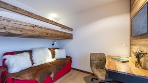 Een gezellige kamer met een rode bank, een houten bureau en een stoel.