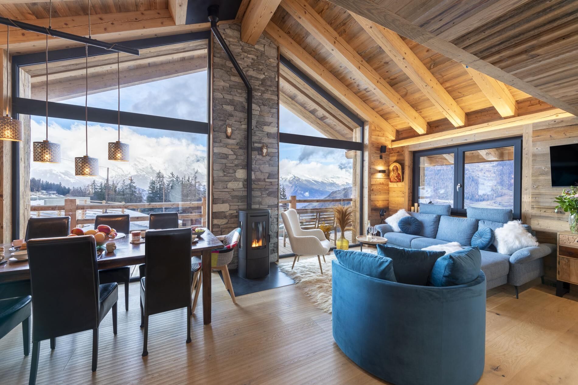 A spacious living area with a stone fireplace, a blue sofa, and a dining table with chairs.