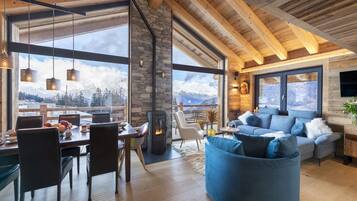 A spacious living area with a stone fireplace, a blue sofa, and a dining table with chairs.