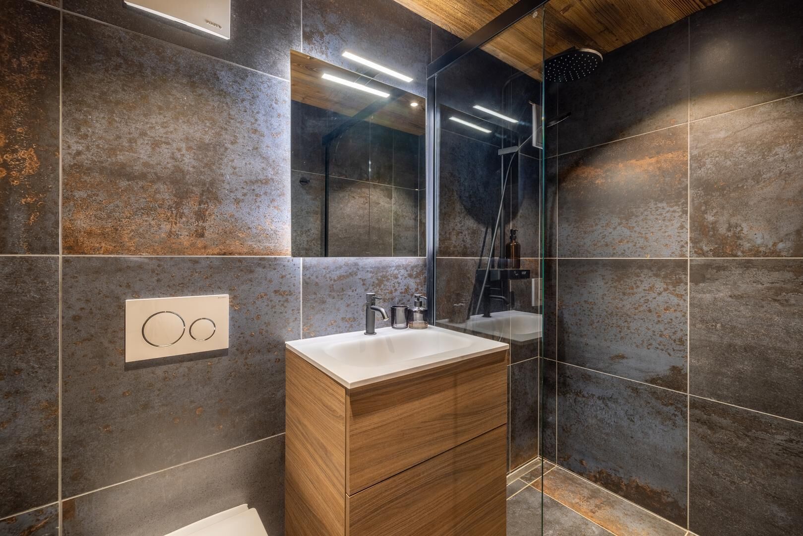 A modern bathroom with a wooden vanity, a large mirror, and a shower area.