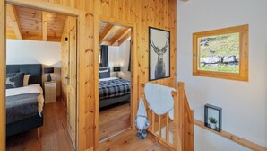 A wooden cabin with a bedroom featuring a bed, nightstands, and a gnome decoration. - Chalet Belle Vue Alpine Charm With a View to Remember (Riddes)