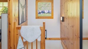 A wooden interior with a gnome decoration, a framed deer picture, and a window with a view of greenery. - Chalet Belle Vue Alpine Charm With a View to Remember (Riddes)
