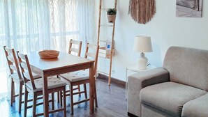 Een moderne woonkamer met een houten eettafel, een beige bank en een ladderplank.