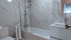 Een moderne badkamer met een douchecabine van glas, een toilet en een wastafel met spiegel.