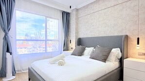 Une chambre moderne avec un grand lit, une vue sur la ville et un radiateur mobile.