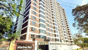 Un immeuble de grande hauteur appelé Marina Bay, doté de nombreux étages et balcons, d’une entrée sécurisée et surplombant un ciel dégagé.