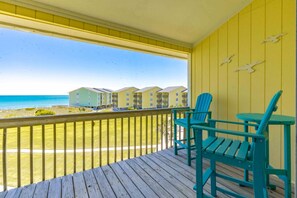 A balcony with a wooden floor, two chairs, and a table.