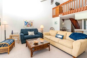 A living room with a sofa, a coffee table, a lamp, and a painting on the wall.