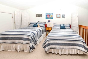 Quarto com duas camas, mesa de cabeceira, luminária e arte na parede.